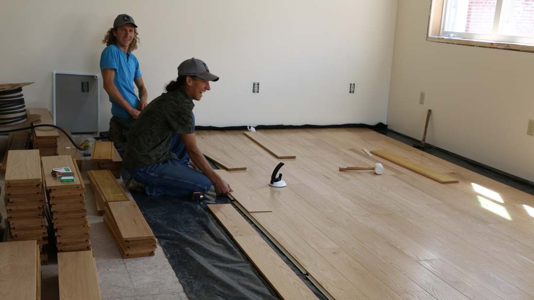 Homeowners installing hardwood floating floors with enthusiasm and focus.